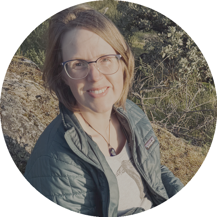Anne-Lynn sitting on a hillside overlooking a lake